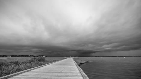 black and white timelapse of an ominous storm moving over a public dock