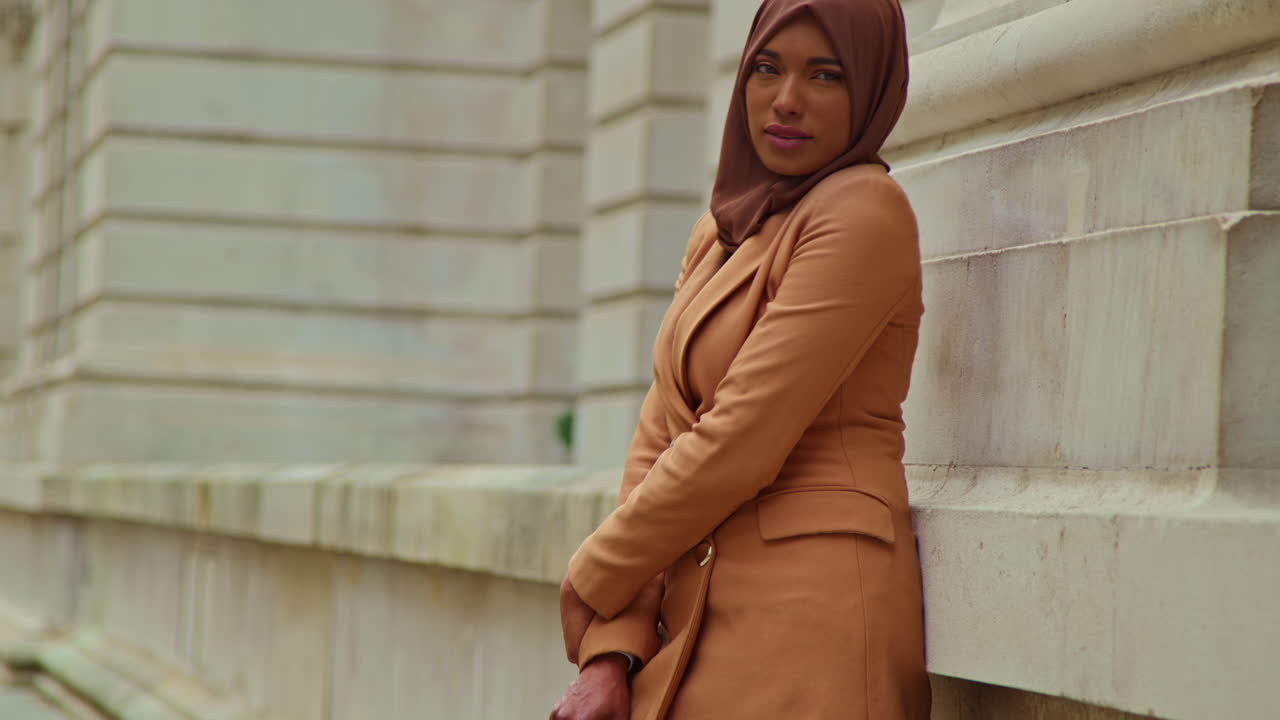 портрет мусульманской бизнесменки в хиджабе и современном деловом костюме, стоящей за пределами городских офисных зданий 1