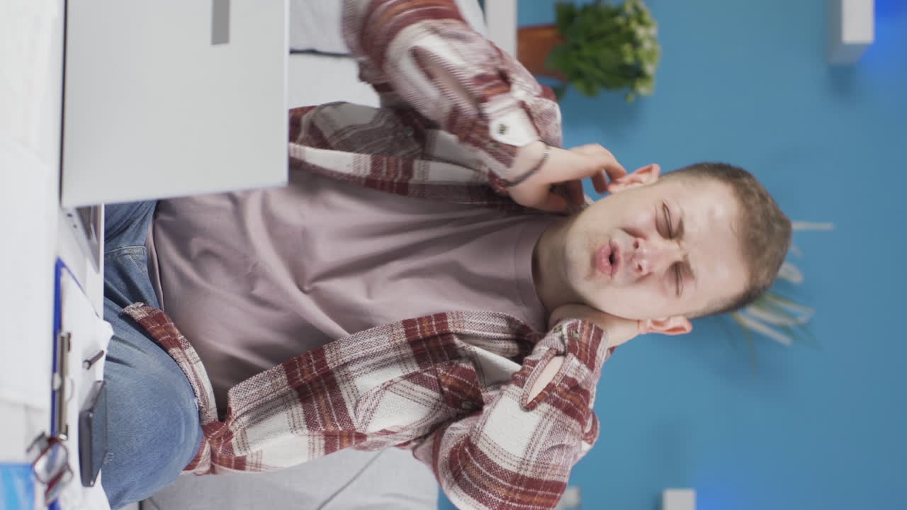 video vertical de un trabajador de oficina en casa hombre tiene dolor de cuello.