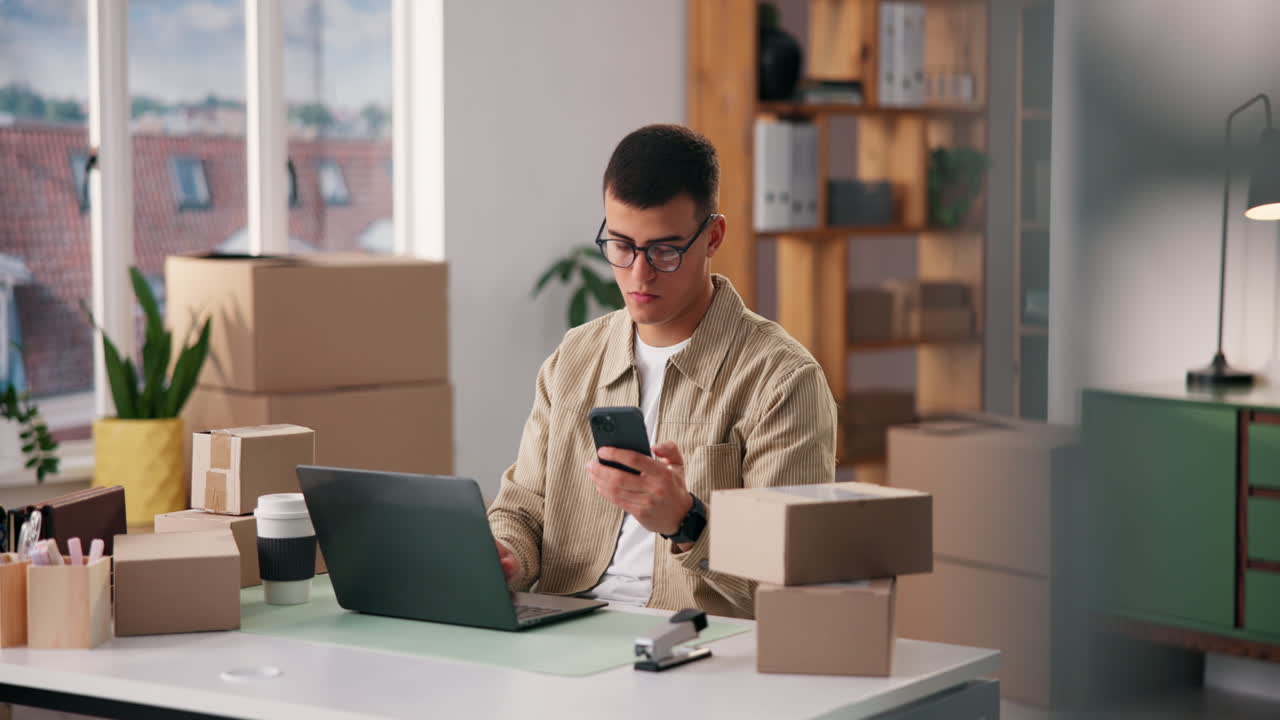 Uomo che lavora al laptop circondato da scatole in un ufficio domestico