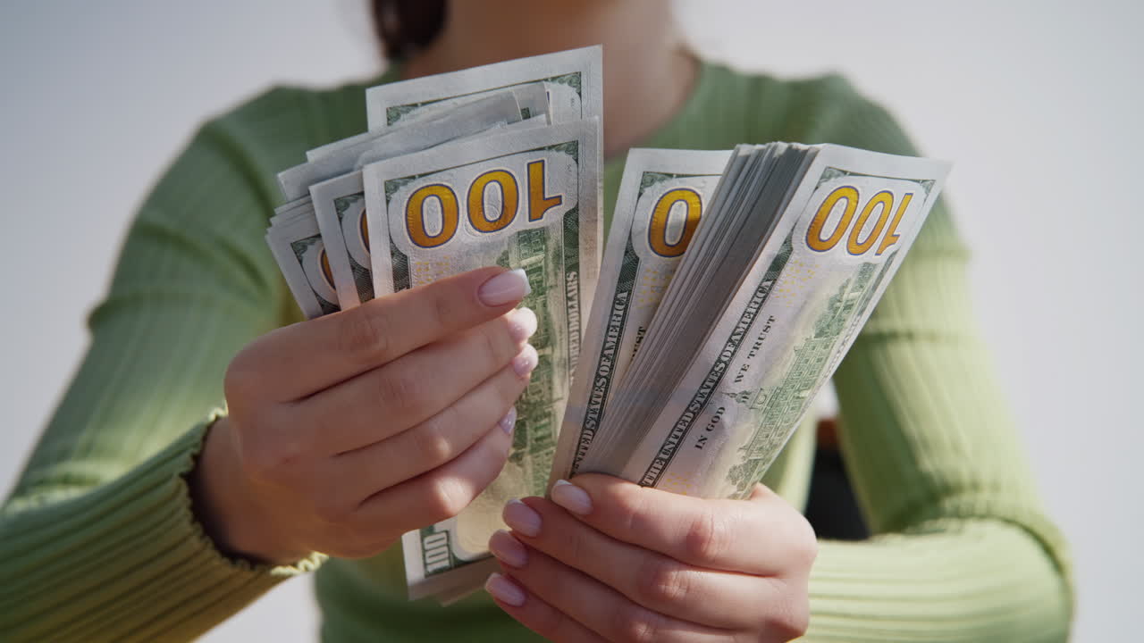 Unknown businesswoman counting dollars calculating banknotes indoors closeup