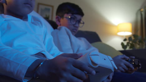 Close-Up-On-Hands-Of-Two-Young-Boys-At-Home-Playing-With-Computer-Games-Console-On-TV-Holding-Controllers-Late-At-Night-4