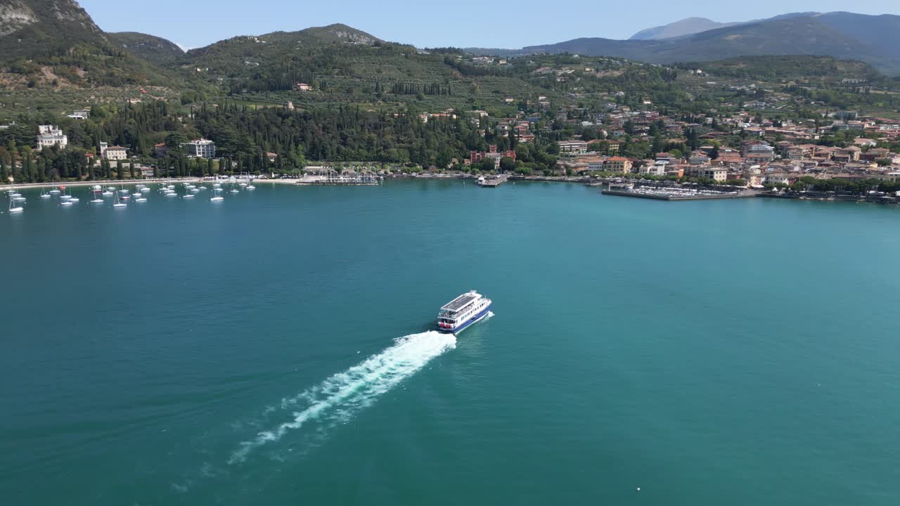 ripresa aerea che segue una grande barca che si avvicina alla costa del garda, lago di garda, italia