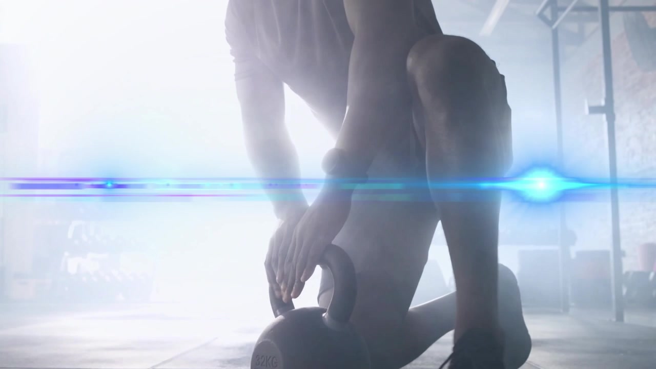 Male athlete stepping to kettlebell, kneeling, gripping and lifting to chest, backlit for fitness