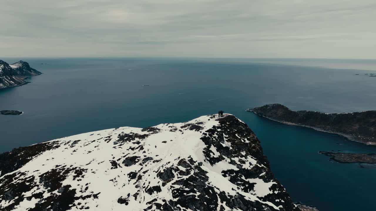People On The Mountain Peaks Of Offersoykammen In The Lofoten Archipelago, Norway. Aerial Drone Shot