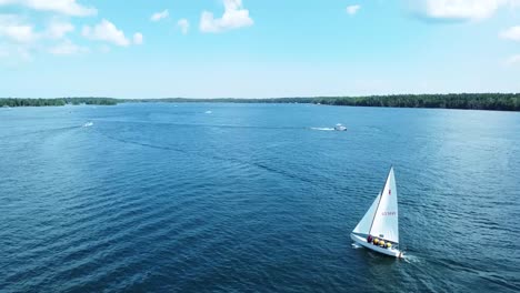 following wide aerial sailboat sailing in sun during summer - hessel, michigan