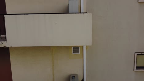 Aerial-view-moving-along-side-upwards-near-the-balcony's-of-residential-building-daytime,-presenting-the-urban-environment-living-settlement