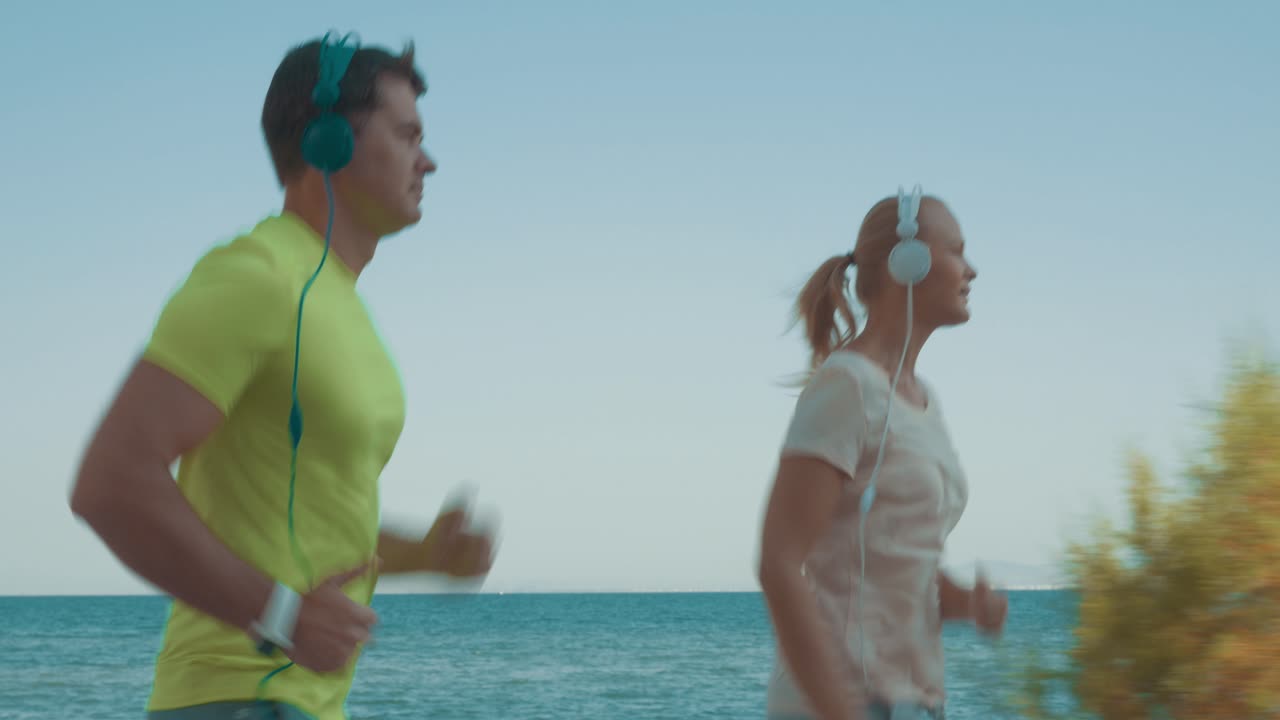 una joven pareja deportiva corriendo con música.
