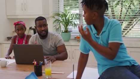 Padre-Afroamericano-Usando-Una-Computadora-Portátil-Y-Ayudando-A-Su-Hijo-Con-La-Tarea-En-Casa