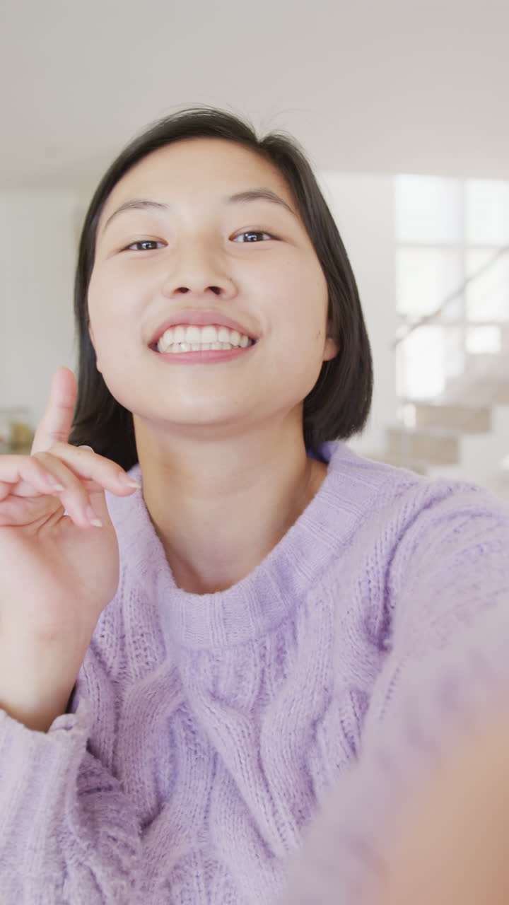 Vertical video of portrait of happy asian woman having video call in living room