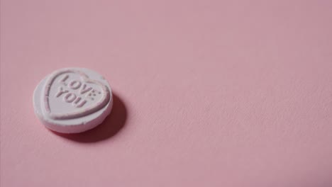 mano recogiendo caramelos de corazón con mensaje romántico te amo sobre fondo rosa