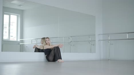 fit meisje in zwarte kleren uitvoert hedendaagse. vrouwelijke danseres toont vloeiende bewegingen, lichaam en handen golven in de witte kamer. moderne ballet dans choreografie. jonge vrouw beweegt soepel