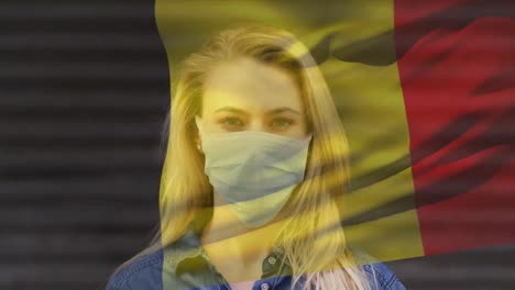 Animation-of-flag-of-belgium-waving-over-caucasian-woman-wearing-face-mask-in-city-street