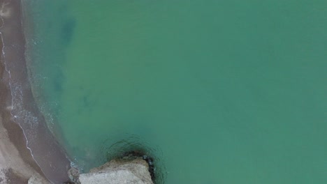 Aerial-birdseye-view-of-abandoned-seaside-fortification-buildings-at-Karosta-Northern-Forts-on-the-beach-of-Baltic-sea-,-waves-splash,-overcast-day,-wide-drone-shot-moving-forward