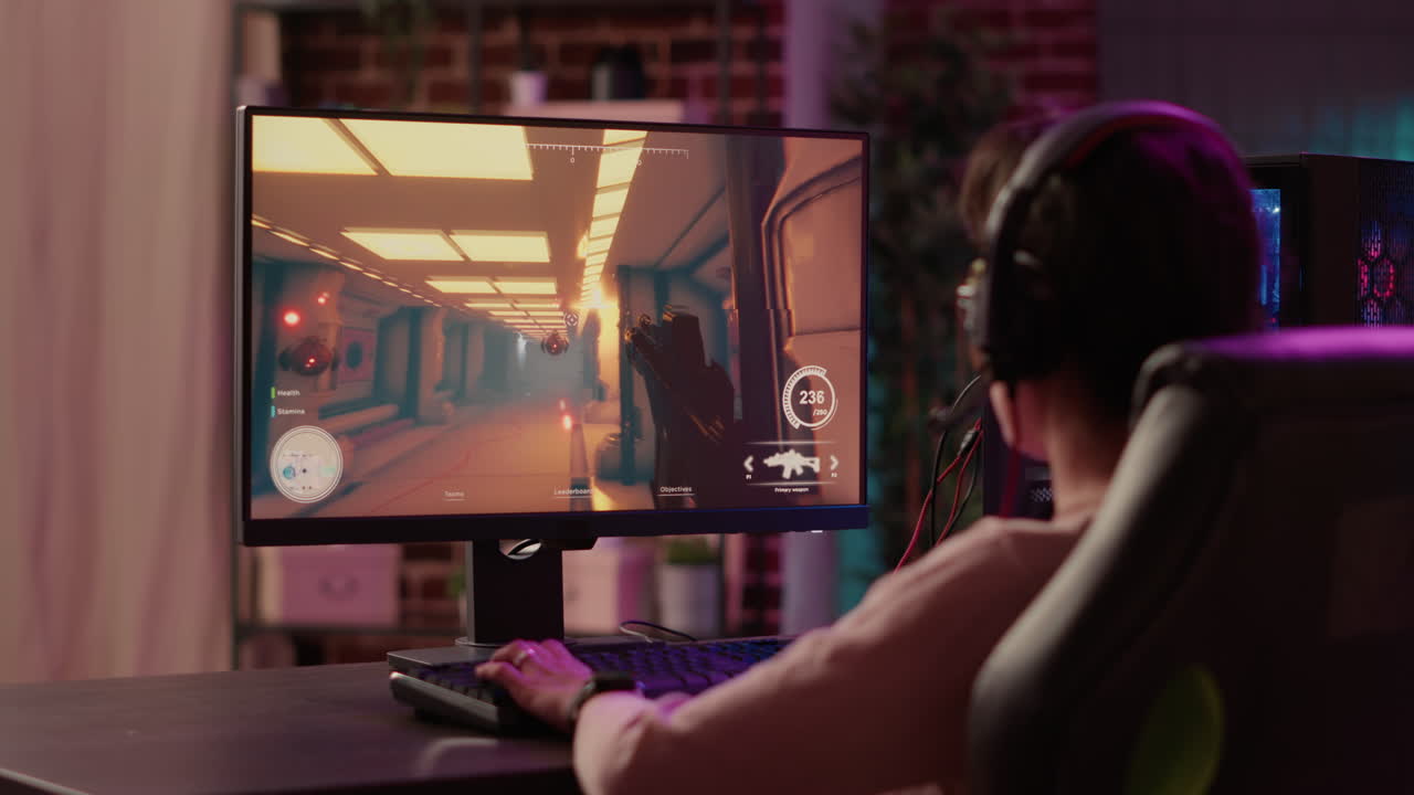 Over shoulder view of gamer girl using pc gaming setup relaxing playing multiplayer online action video game