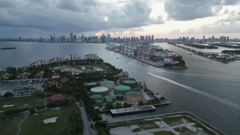 Aerial-view-of-Fisher-Island-in-Miami-Dade-County-under-stormy-sky-at-sunset-with-Downtown-Miami-skylines-in-the-background,-Florida,-USA