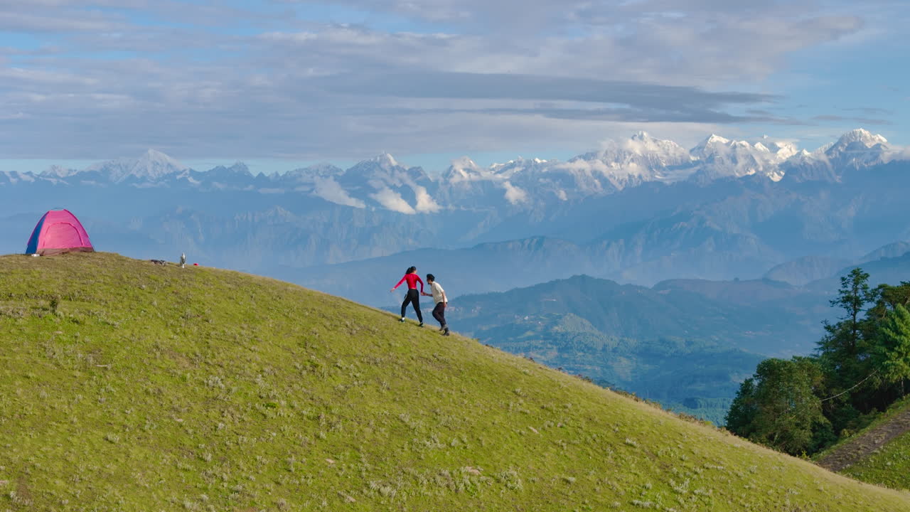 Drone shot captures Nepali couple running and enjoying fun morning on hills of Shailung Dolakha near Tibet they explore the mountains, camp, dance, and sing together in this beautiful natural setting
