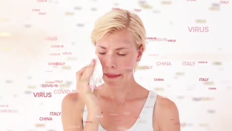Animation-of-words-Covid-19-and-country-names-floating-over-Caucasian-woman-sneezing-into-a-tissue