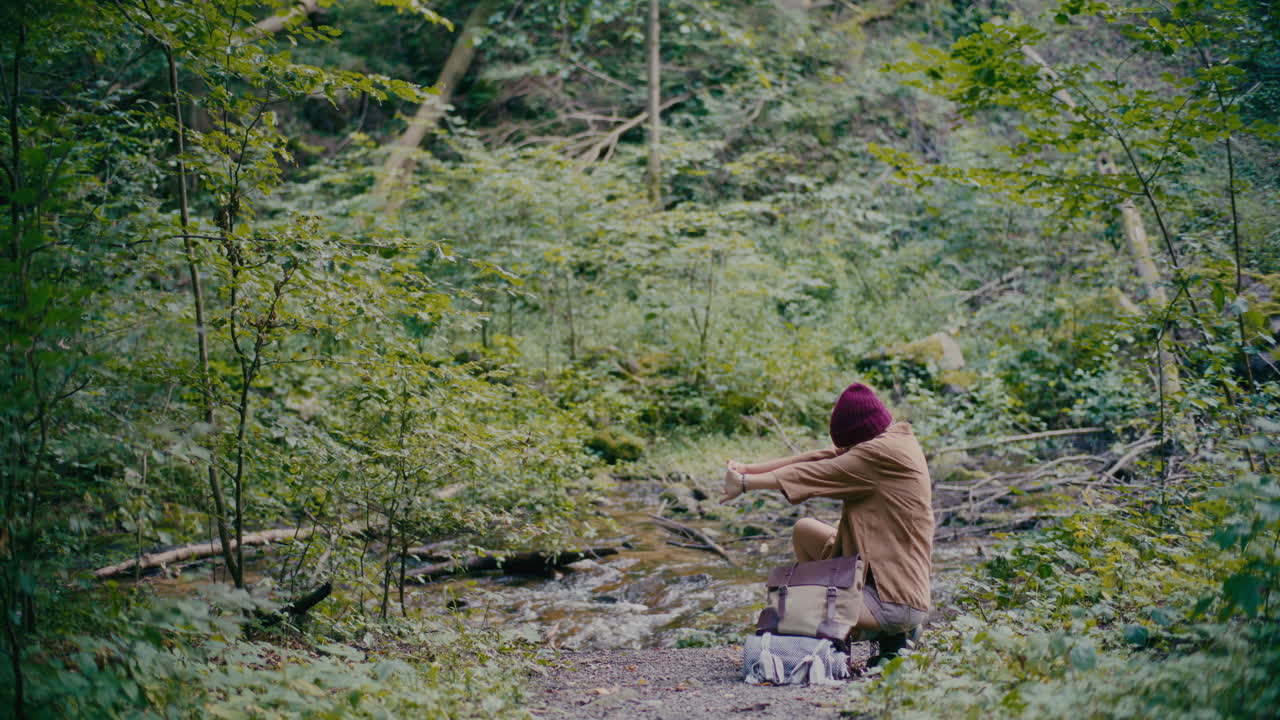 숲 속 의 하천 근처 에  ⁇ 어 있는 젊은 관광객