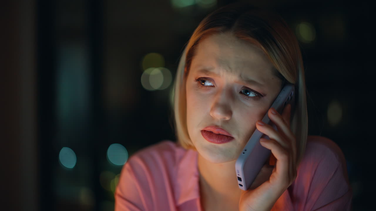 Sad woman talking on the phone at night