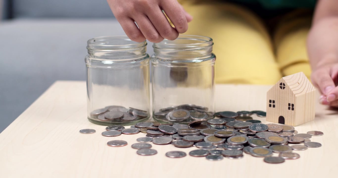 A person sorts coins into jars reflecting financial organization and saving strategies.