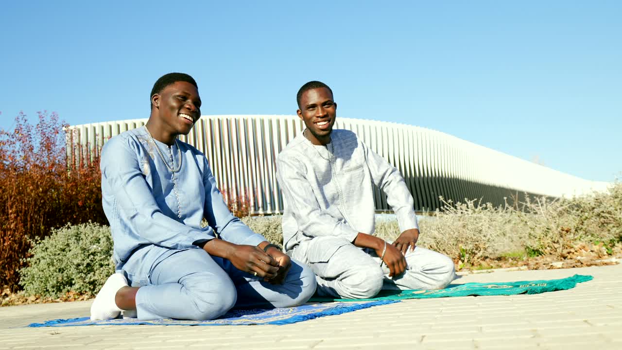 Two Muslim Men Sitting on Prayer Mat Outdoors