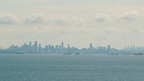 vancouver city skyline view from english bay, cargo vessels in foreground