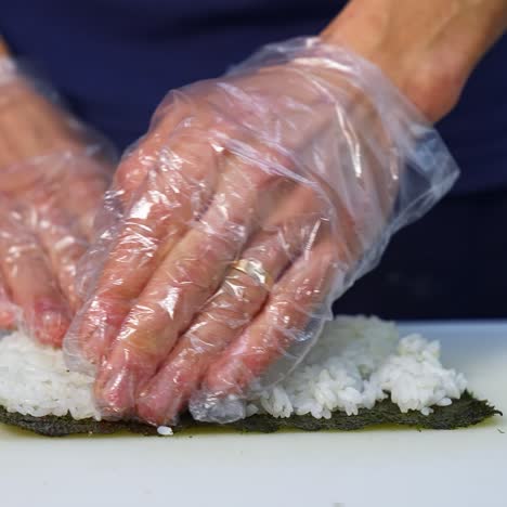 chef in gloves is preparing sushi. sushi are made of rice, nori seaweed, cucumber, cream cheese. appetizing and nutritious food concept