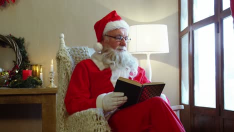 santa claus mirando por la ventana mientras lee una novela