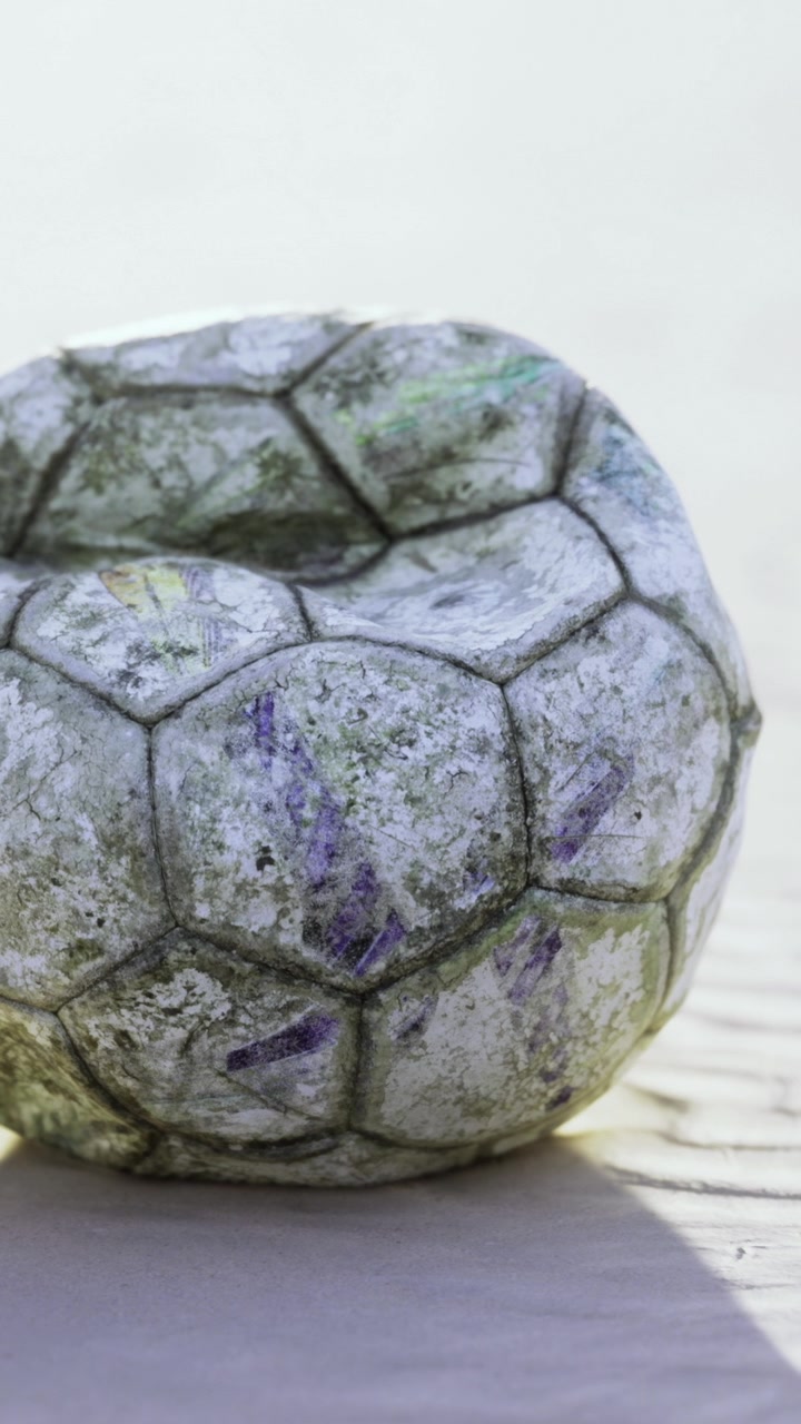 Gammel fotball på bakken som viser slitasje fra bruk og tid