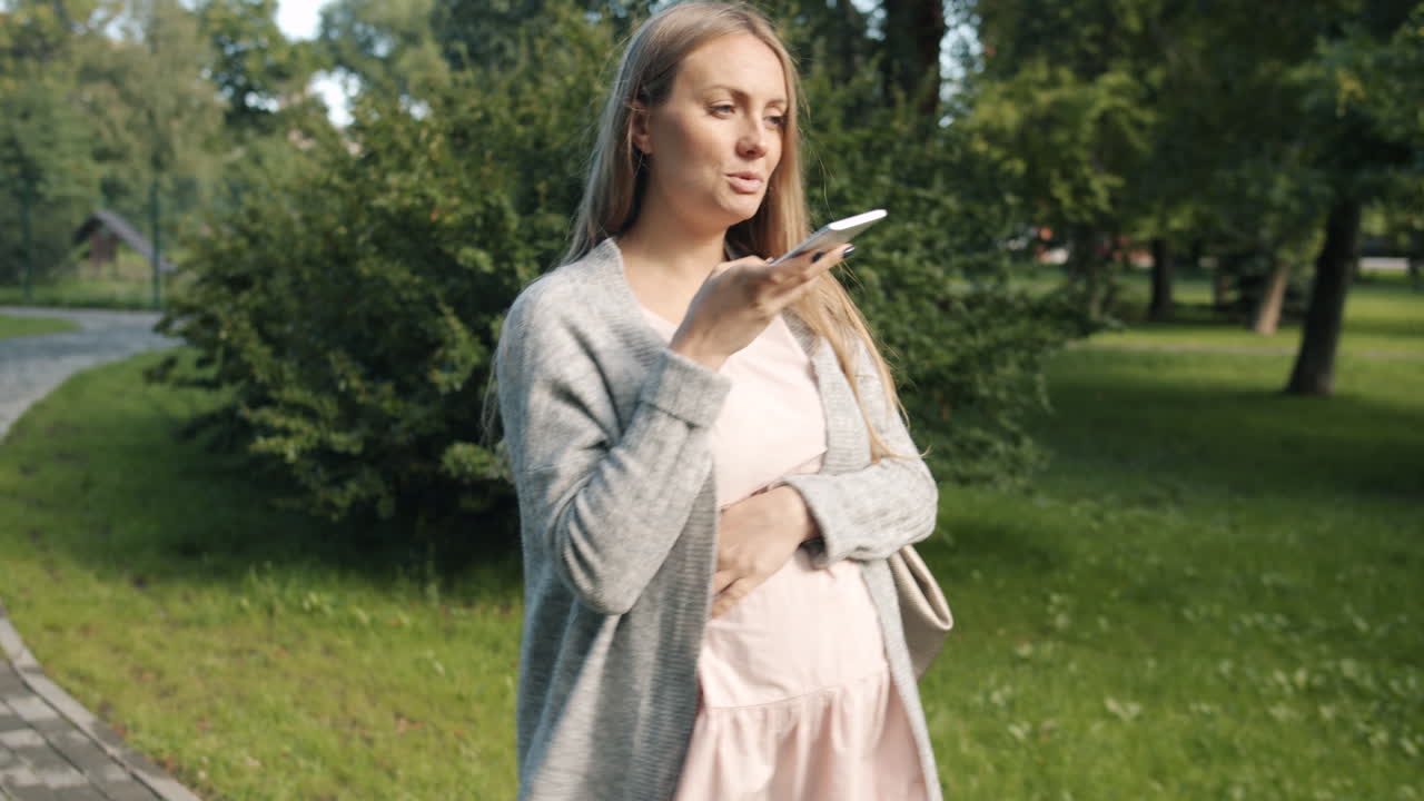 Mulher grávida falando ao telefone no parque