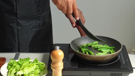 man cooking green beans on electric stove