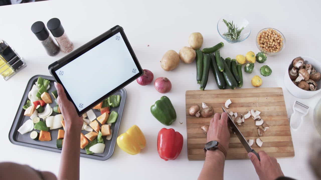 젊은 백인 남성과 아프리카계 미국인 여성이 집에서 음식을 준비하고, 복사 공간이 있습니다.