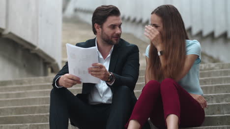 Joyful-business-man-and-business-woman-discussing-results-on-documents-in-city