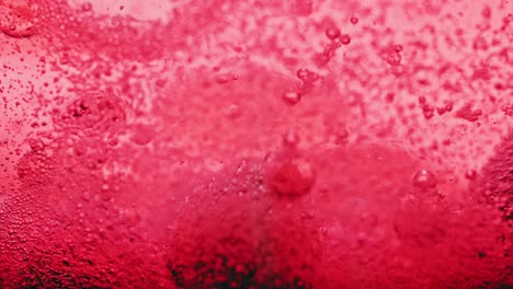 tiro macro de burbujas rojas goteando y moviéndose en agua roja brillante