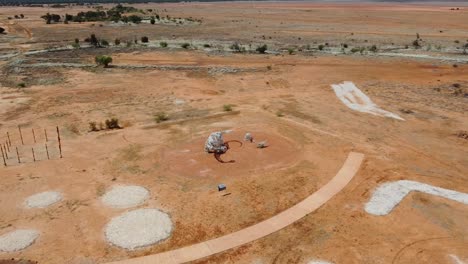 vista aérea de una extraña estatua de dinosaurio cerca de una pequeña ciudad en el interior de australia