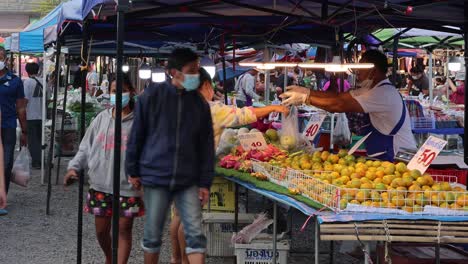 shoppers and vendor interact at a busy market.