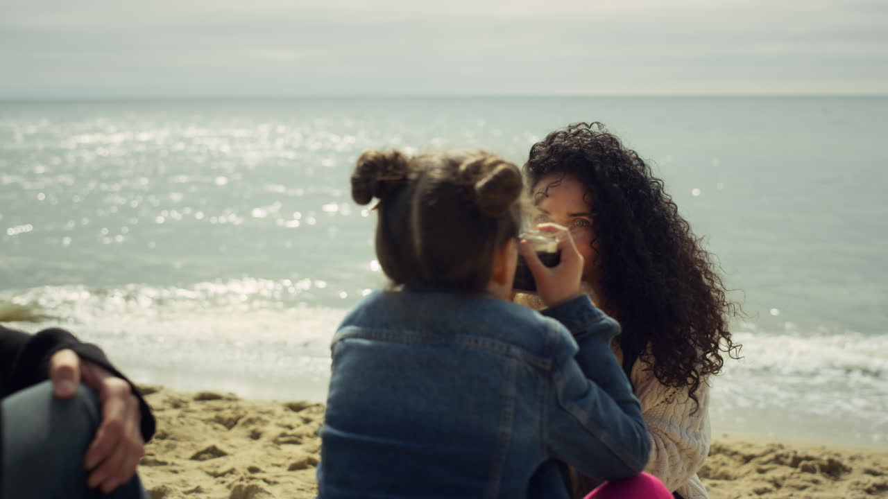 familia encantadora jugando a fotografiar en la playa. madre hijo tomando fotos al aire libre.