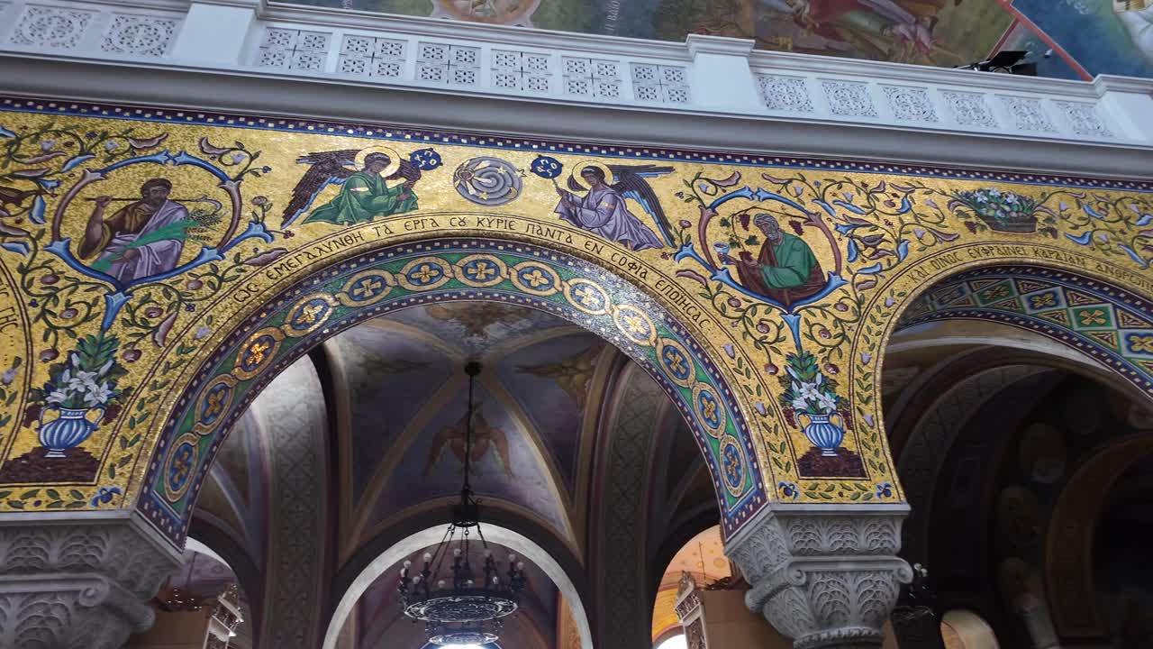 Patras,Interior of Saint Andrew's Church,Footage slides from left to right going through the colorful arches with fresco's and 2nd floor than descends slowly to the main floor at the seating area