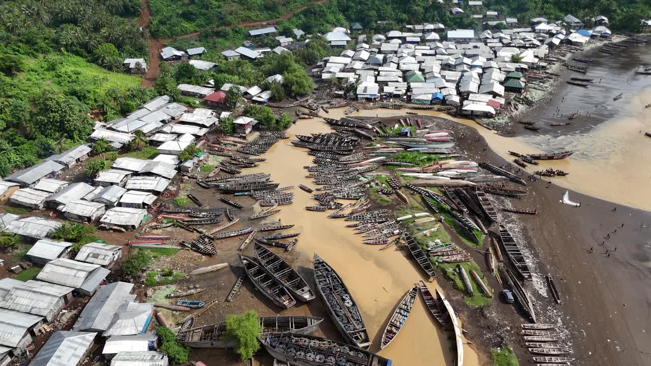 Perspektif drone ketinggian tinggi yang detail menampilkan air sungai yang keruh dan berwarna cokelat mengalir ke laut di sepanjang garis pantai Limbe di Kamerun