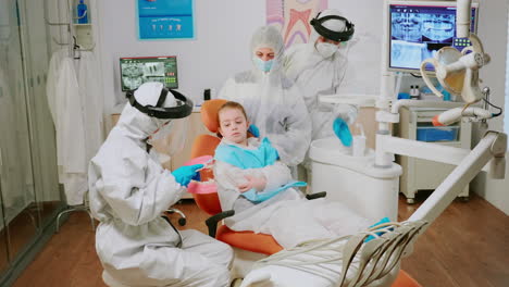 dentist doctor in coverall showing to kid the correct dental hygiene