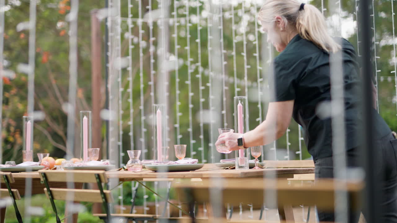 Wedding Planner Styling Reception Dinner Table With Candles And Glasses In Beautiful Outdoor Garden, 4K Slow Motion