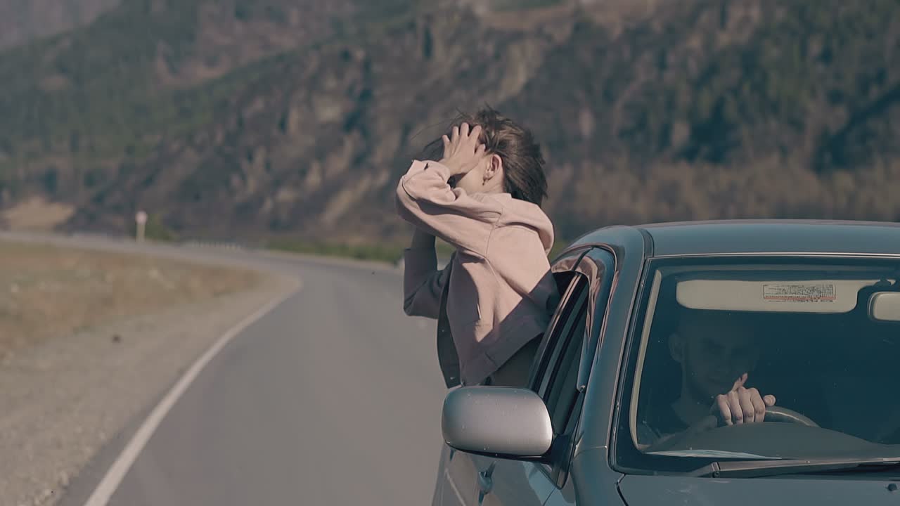 mujer de cabello claro se inclina hacia fuera de un coche de época y sonríe