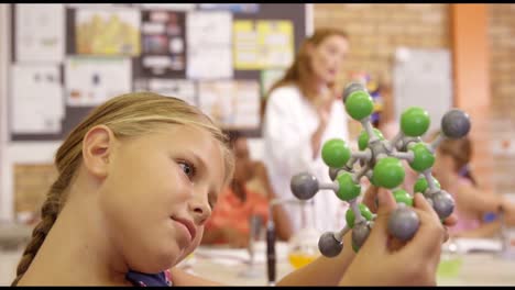 Schoolgirl-holding-molecule-model-in-laboratory