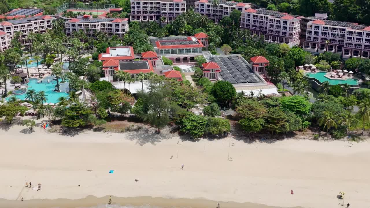 Aerial view of a beachfront resort featuring turquoise pools, lush gardens, and sandy shores.