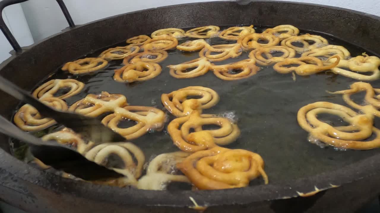 Raw jilapi deep frying 4k video clip.Jilapi making on a hot big pan.Jalebi, also known as jilapi, jilebi, jilipi, zulbia, jerry, mushabak, or zalabia, is a popular Indian sweet snack.