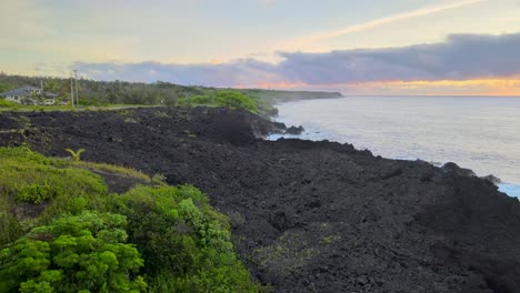 Fesselnde-Drohnenaufnahme,-Die-Ein-Altes-Lavafeld-Auf-Big-Island,-Hawaii,-Enthüllt,-Das-Während-Des-Magischen-Sonnenuntergangs-Von-Einer-Straße-Am-Meer-Umarmt-Wird