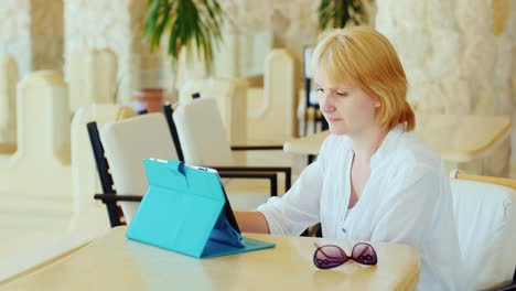 A-Female-Tourist-Enjoys-The-Tablet-She-Is-Relaxing-At-Tables-In-A-Cafe-Always-On-Line-Internet-On-Va