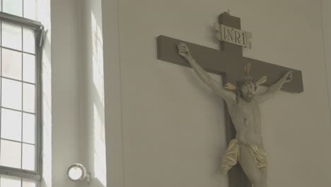 Camera-pans-to-a-crucifix-in-a-church,-chandelier-in-the-foreground