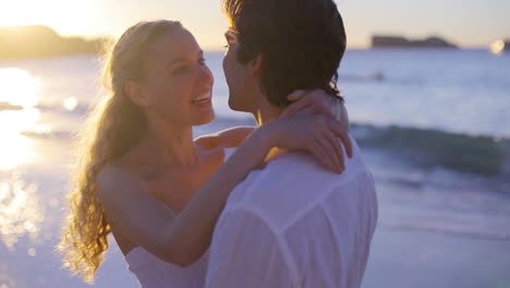 Pareja-En-La-Playa-Besándose-Durante-El-Atardecer-Y-Luego-Corriendo-Hacia-El-Mar